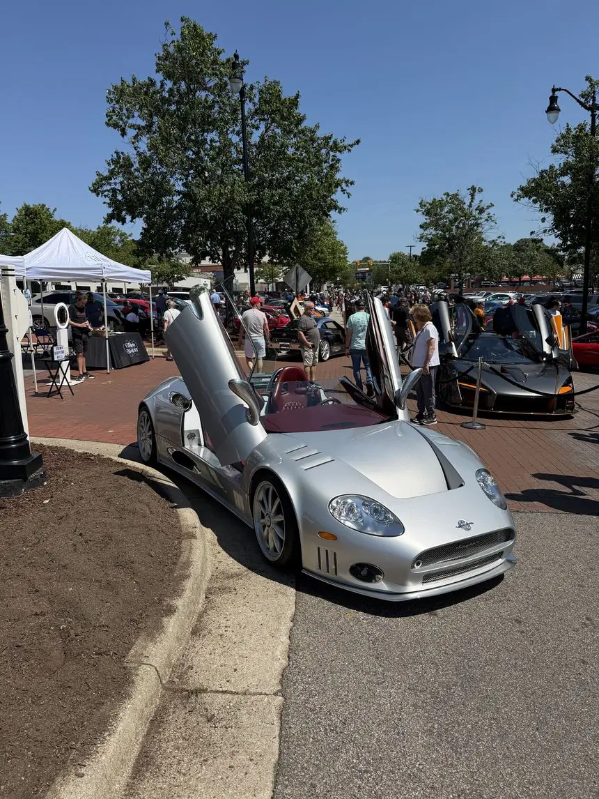 A Spyker C8 with its doors raised at a Cars & Coffee meet