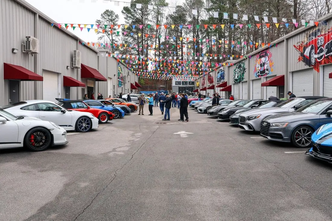 Cars and Coffee filling the CECC courtyard, bunting overhead and murals on the garage doors